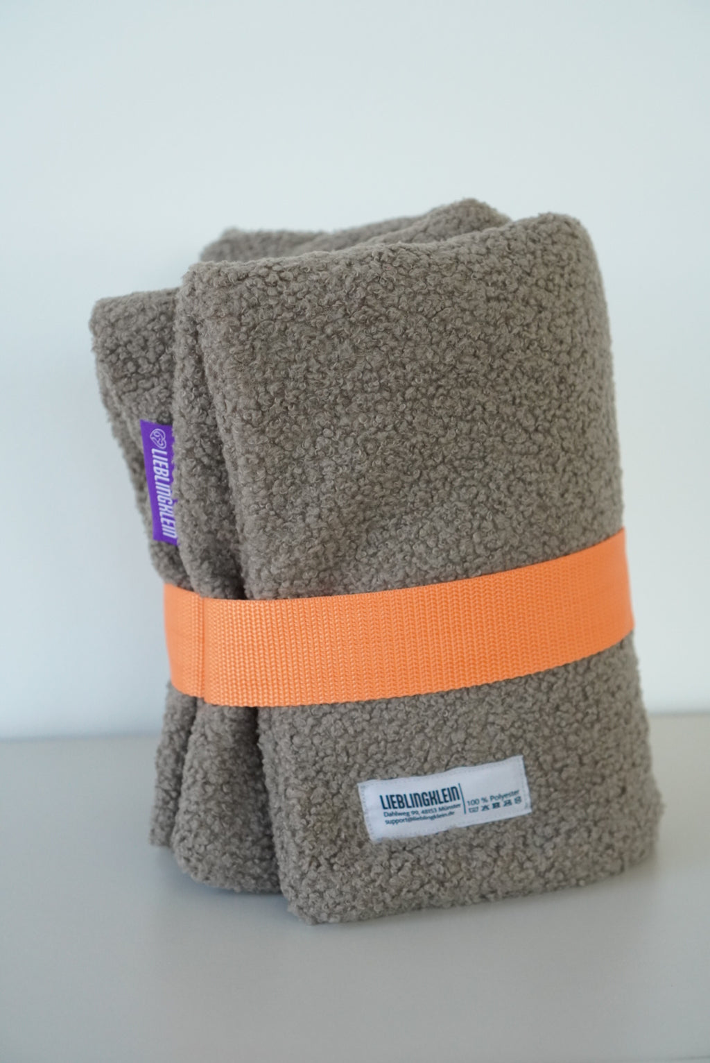 PLACE Hundedecke Taupe gefaltet mit orangenem Gurt und Waschzettel