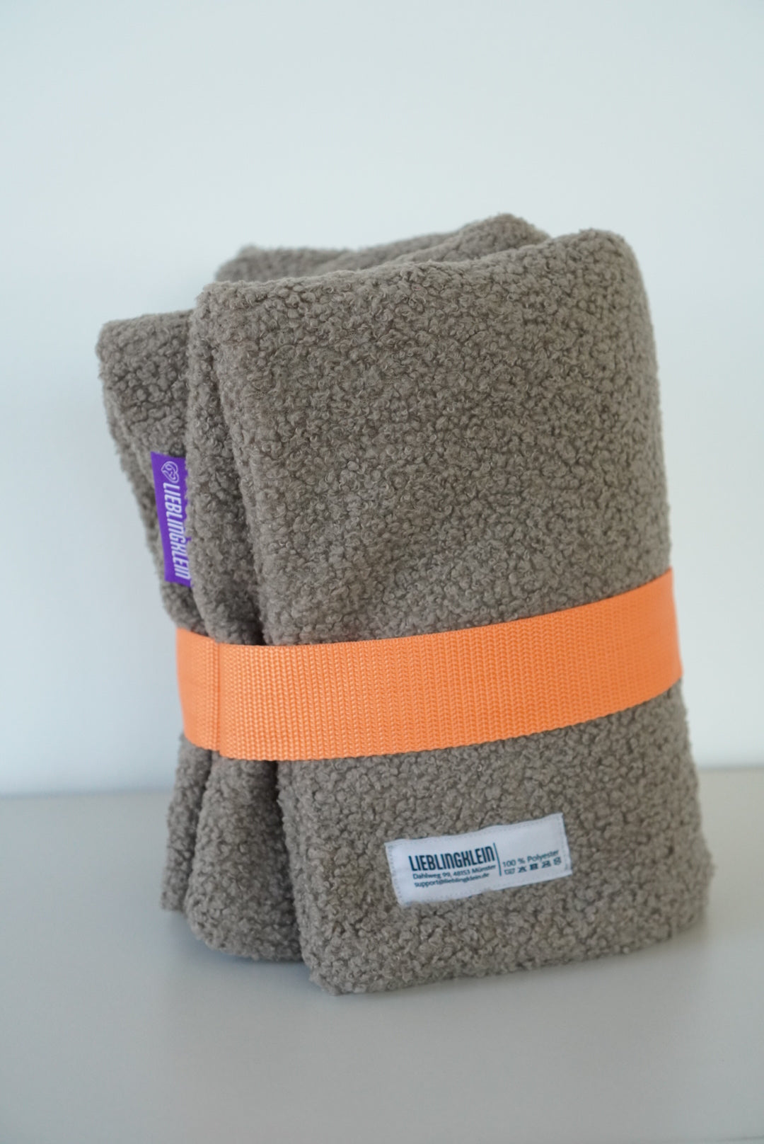 PLACE Hundedecke Taupe gefaltet mit orangenem Gurt und Waschzettel