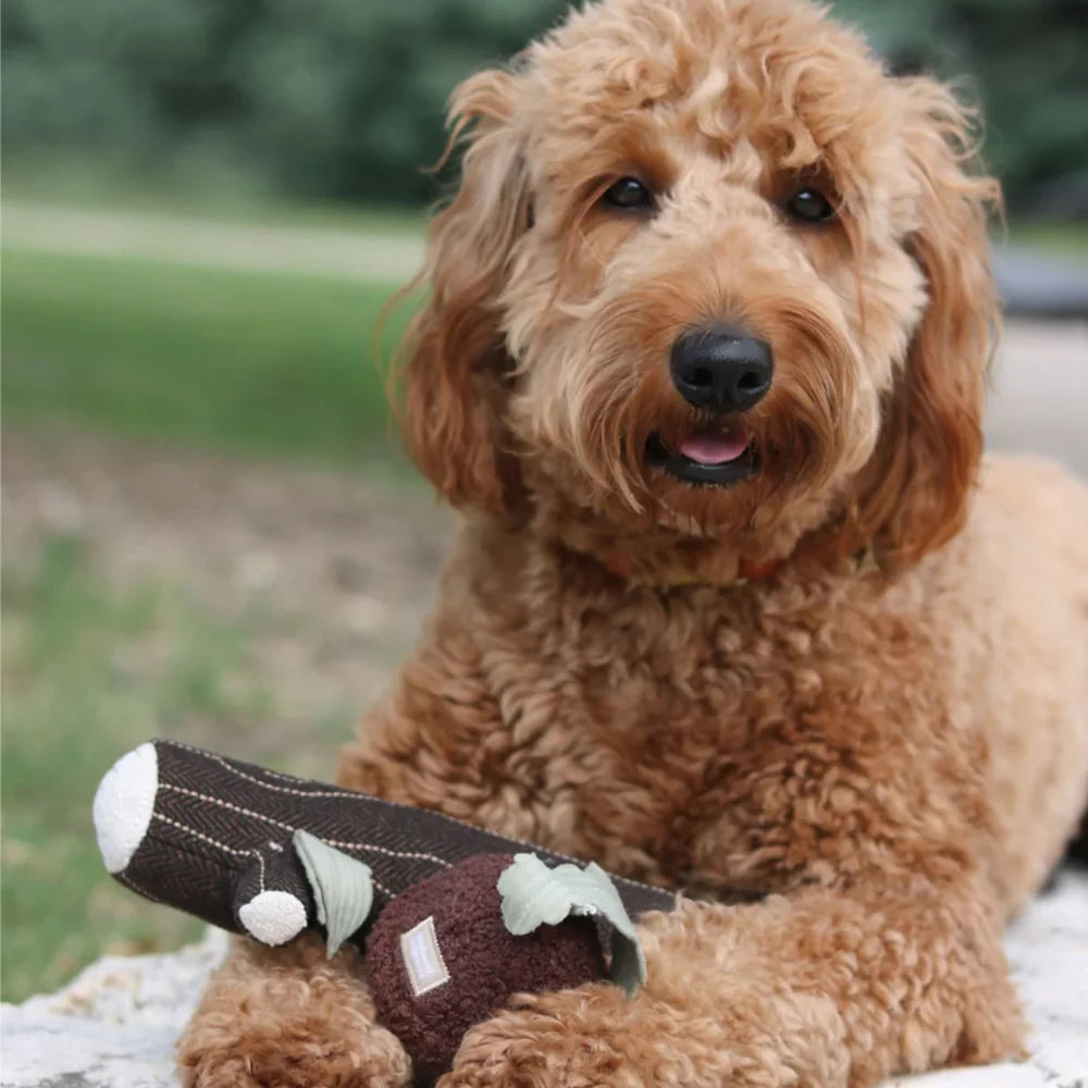 Hund liegt entspannt mit dem FIRE LOG von Lambwolf – stylisches Spielzeug im Fischgrät-Look